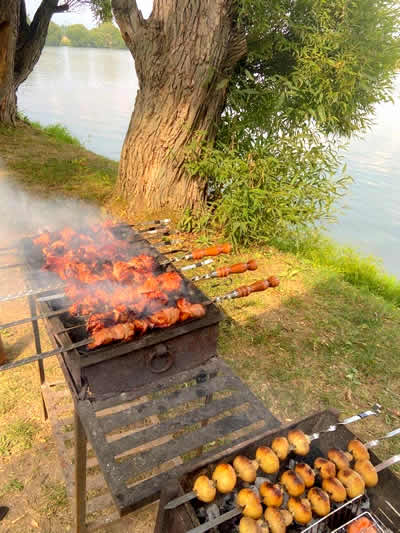 Traditional Russian shashliki grilling outdoors beside a river at a countryside dacha