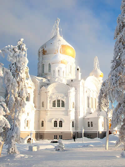 Perm, Russia. A large, pristine white Russian Orthodox cathedral with a massive golden onion dome and smaller side domes.