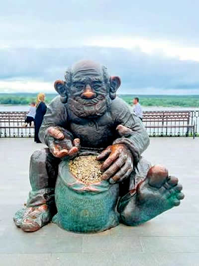 Perm, Russia. A whimsical bronze statue of a large-eared, barefoot, bearded character sitting cross-legged on the ground.